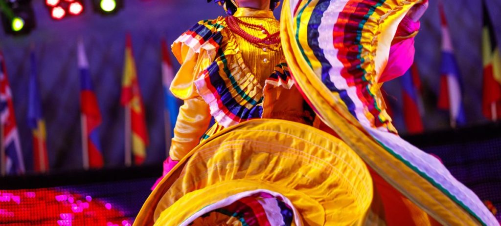 A dancer in a yellow dress performs a Folklorico dance