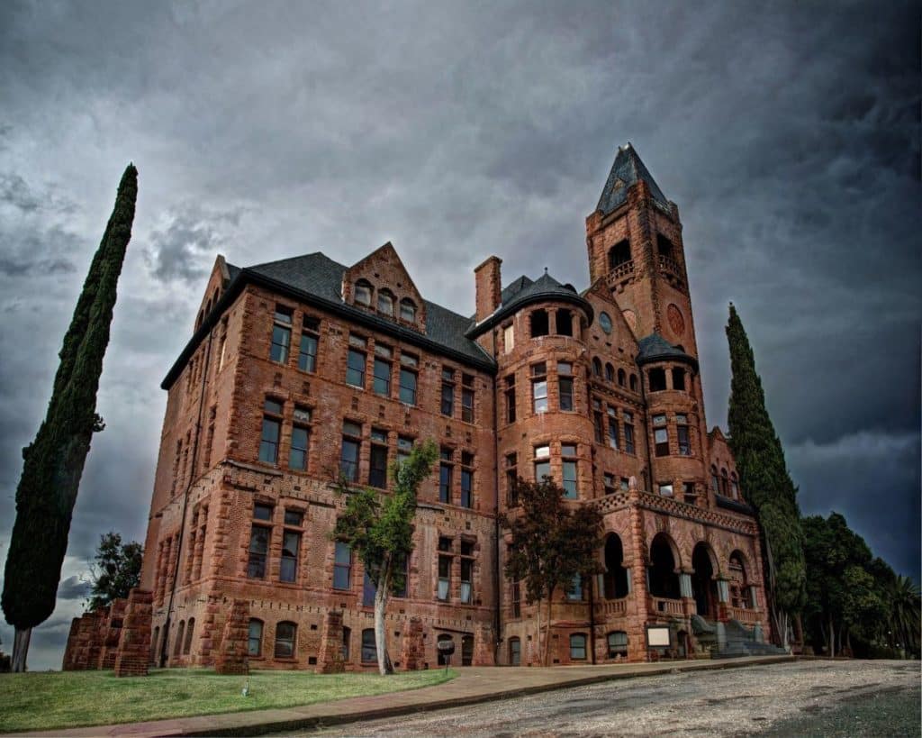 A red brick castle-looking building against a stormy sky.