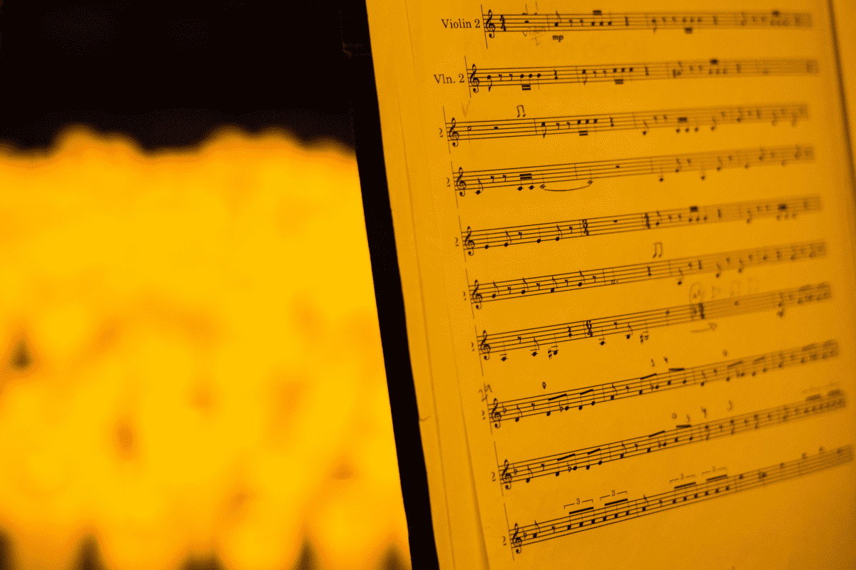 A close up of a music sheet in the glow of candlelight.