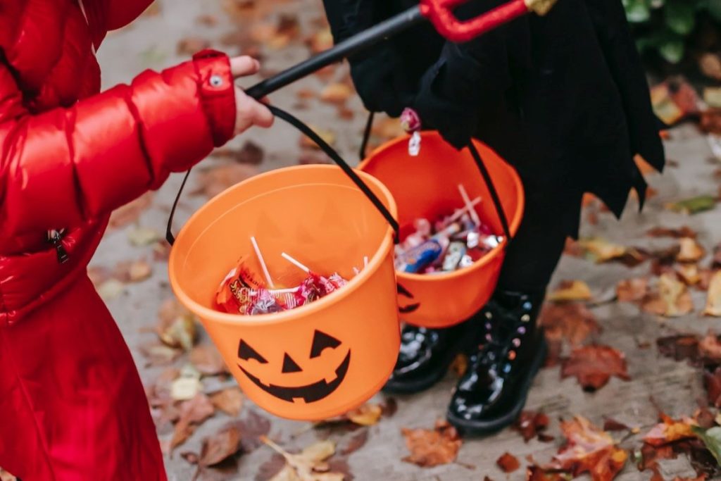 Anonymous kids in costume holding pumpkin baskets full of candy.