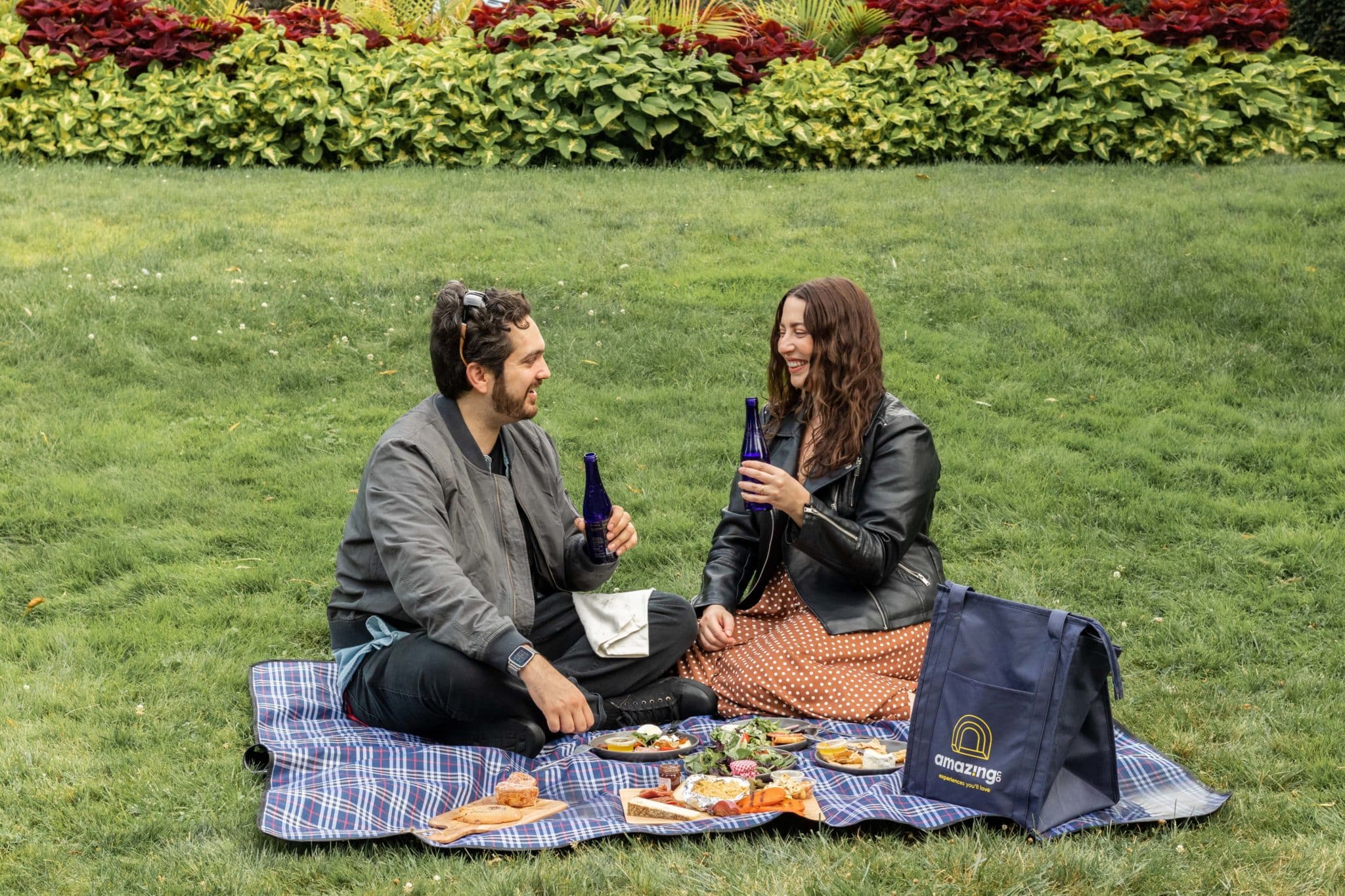 A man and a woman have a picnic outdoors. 