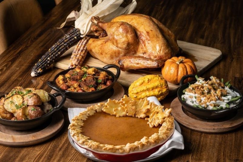 Thanksgiving meal from International Smoke with a turkey, stuffing, roasted potatoes, green bean casserole, and a pumpkin pie.